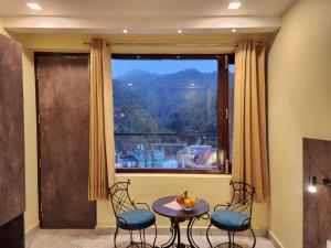a room with a table and chairs and a large window at The White Orchid Dalhousie in Dalhousie