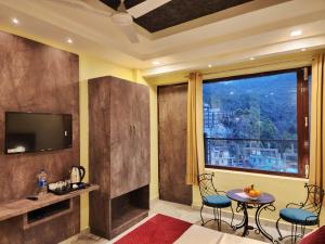 a living room with a television and a table and chairs at The White Orchid Dalhousie in Dalhousie