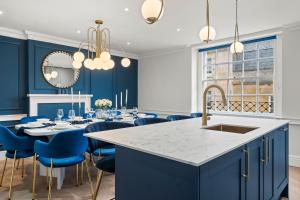 a kitchen with blue cabinets and a table with blue chairs at Baths Ultimate House Sleeps 40 in Bath