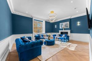 a living room with blue walls and blue couches at Baths Ultimate House Sleeps 40 in Bath