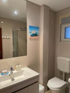 a bathroom with a sink and a toilet and a mirror at OuraSea Apartment in Albufeira +45 photos