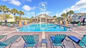una piscina con sillas azules y palmeras en Villas at Seven Dwarfs - Close to Disney, en Kissimmee