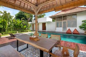an outdoor patio with a wooden table and chairs next to a swimming pool at Omaneil Villa in Uluwatu +14 photos