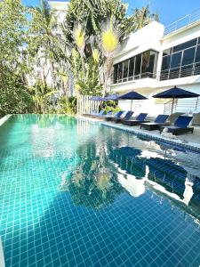 Una piscina con sillas y sombrillas al lado de una casa. en Cozy apartment Karon, en Phuket