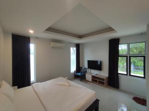a bedroom with a bed and a flat screen tv at Baan Ampai Beach Hotel in Hua Thanon Beach