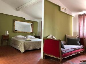 a bedroom with a bed and a chair and a mirror at La Maison d'Odette in La Ciotat
