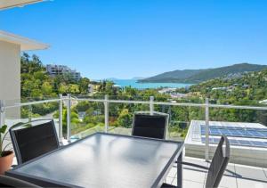 Un patio con una mesa y sillas en un balcón. en 52 Airlie Beach Beauty at The Summit, en Airlie Beach