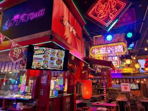 un restaurante con letreros de neón y un bar con mesas en Full House Rent in Tokyo Ghibli Sakura Shinjuku 1H, en Higashi-murayama