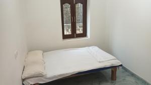 Sujata Buddha Homestay في بود جايا: سرير صغير في غرفة بيضاء مع نافذة