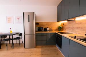 Una cocina con refrigerador de acero inoxidable y una mesa. en Krivoo Apartments II-Private Parking, en Košice