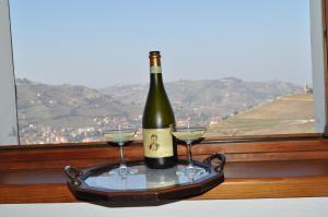 eine Flasche Wein und zwei Gläser auf einem Tablett in der Unterkunft Agriturismo Ai Piacentini in Santo Stefano Belbo