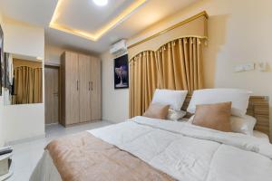 a bedroom with a large white bed in a room at LOUIS Apartment in Ikota