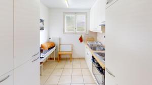Una cocina con gabinetes blancos y un fregadero. en Pace PC1, en Blatten bei Naters