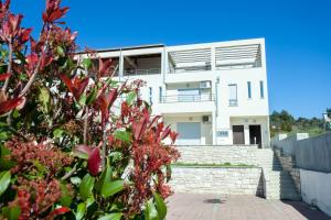 Uma casa branca com flores vermelhas à frente. em Deluxe Neli Apartments em Zadar