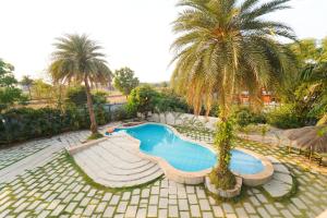 a swimming pool with palm trees in a courtyard at Voyage Zo Lonavala in Lonavala
