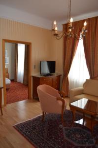 a living room with a couch a chair and a tv at Hotel Jäger in Vienna