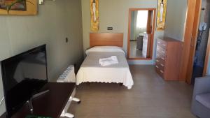 1 dormitorio con 1 cama y TV de pantalla plana en Hostal Playa Mazagon (El Remo), en Mazagón