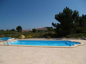 a large swimming pool in a yard with a tiled patio at Casa do Parque in Aljezur