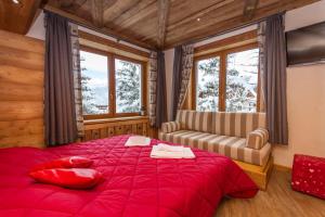 Schlafzimmer mit einem roten Bett, einem Sofa und Fenstern in der Unterkunft Hotel Sauze in Sauze dʼOulx