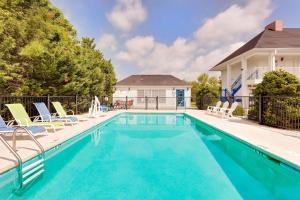 a swimming pool with chairs and a house at Baymont by Wyndham Cleveland in Cleveland