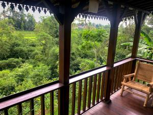 a porch with a chair and a view of the forest at Kubu Damai Guest House in Jatiluwih