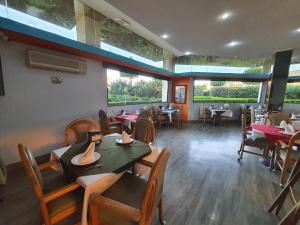 a dining room with tables and chairs and windows at Hotel Alcampo in Querétaro