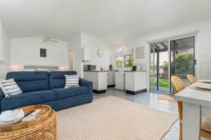a living room with a blue couch and a kitchen at Surfrider Studio - Pet Friendly - 50m to Beach! in Culburra Beach