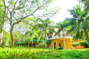 ein gelbes Haus mit Bäumen davor in der Unterkunft The Yala Vista in Tissamaharama