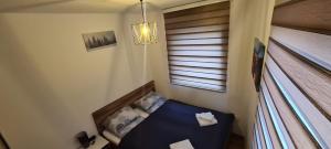 Una pequeña habitación con una cama y una ventana. en Stars Apartman Jahorina, en Jahorina