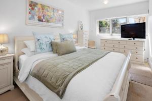 een witte slaapkamer met een groot bed en een flatscreen-tv bij Coral Rose Cottage in Capel Sound