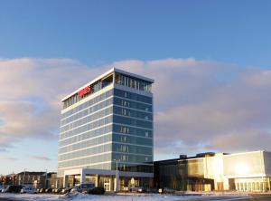 Un edificio alto de cristal con un cartel. en Grand Times Hotel Drummondville, en Drummondville