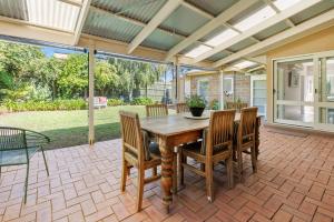 een patio met een houten tafel en stoelen bij Coral Rose Cottage in Capel Sound