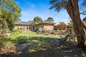 een parkbankje voor een huis bij Coral Rose Cottage in Capel Sound