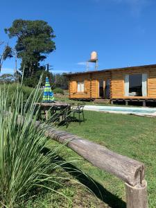 un banco de madera frente a una cabaña de troncos en Cabaña La Rosa, en Chapadmalal