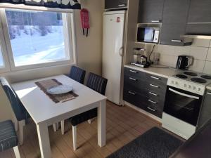 a small kitchen with a white table and a table and chairs at Lake Cottage Onnenranta in Kolinkylä +22 photos