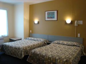 a hotel room with two beds and two lights on the wall at Hôtel Saint Sébastien in Lourdes