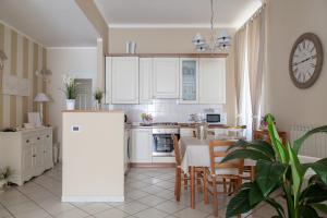 cocina con armarios blancos, mesa y sillas en La Maison Des Anges, en La Spezia