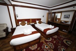 a hotel room with two beds and a mirror at Hotel Sikkim Tourist Centre in Pelling +1 photo