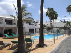 a resort with a swimming pool and palm trees at Departamento Barcaro 2 in Puerto del Carmen