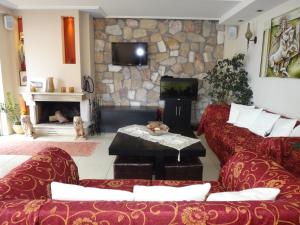 a living room with two red couches and a stone wall at 9 Queens Spa Hotel in Loutra Edipsou