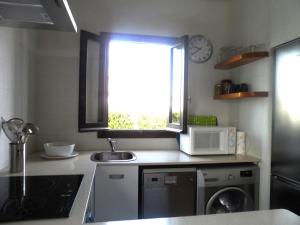a kitchen with a sink and a microwave and a window at Nachetes 1 in Cala Blanca