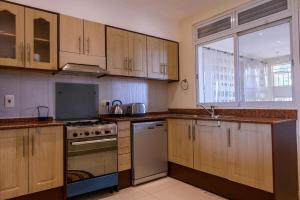 a kitchen with wooden cabinets and a stove and a window at 3 Bed Luxury Condo in Lubowa in Kampala