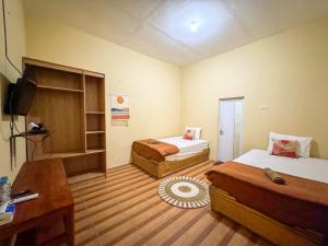 a hotel room with two beds and a television at Hai Surf Camp in Karbang