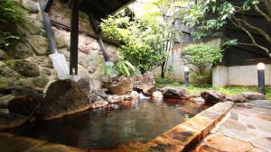 a pool of water next to a stone wall at Ryokan Maruya in Yufuin