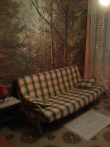 un divano in una stanza con un dipinto di La Valle dell'Etna a Zafferana Etnea