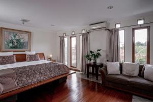 a bedroom with a bed and a couch and windows at Pasteur Beautiful Luxury Home in Bandung