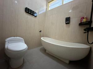 ein Badezimmer mit einer weißen Badewanne und einem WC in der Unterkunft Puri Sagan in Yogyakarta + 21 Fotos