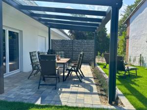 une terrasse avec une table et des chaises sous une pergola bleue dans l'établissement Ferienhaus Ellomi - Klausdorf, à Klausdorf
