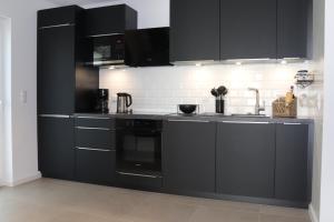 - une cuisine avec des placards noirs et un évier dans l'établissement Ferienhaus Ellomi - Klausdorf, à Klausdorf 29 autres photos