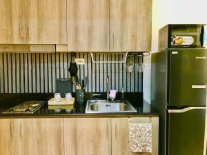 a kitchen with a sink and a black refrigerator at FameStaycation at FAME Residences in Manila